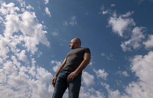 Low angle view of adult man against cloudy sky
