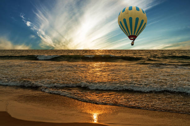 istock Sunset ocean waves with flying hot air balloon. 1400373268