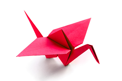 Red paper crane origami isolated on a blank white background.