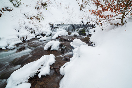 Winter mountain waterfall snow scene. Snowy mountain waterfall landscape. Winter mountain waterfall in Shipot waterfall - Carpathian Mountains, Ukraine