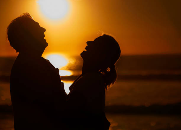 istock Silhouette affectionate senior couple sharing an intimate moment on the beach. Backlit happy husband and wife enjoying a summer day by the sea. They love spending time together on the coast at sunset 1400379193
