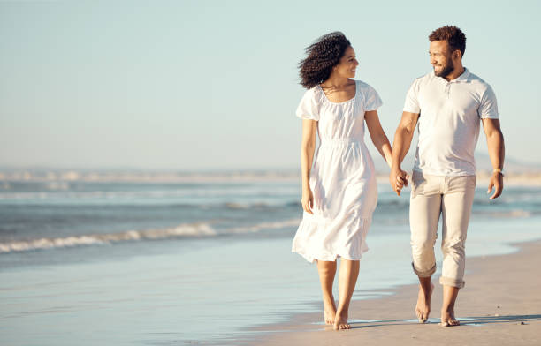 istock Happy mixed race young couple holding hands while walking on the beach together. Hispanic couple traveling and enjoying vacation and being romantic on the beach 1400381470