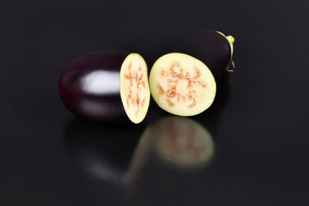 Ripe juicy cut eggplant on a mirror plate on a black background. High resolution photo. Full depth of field.