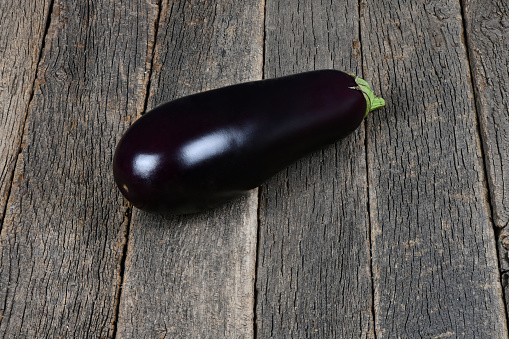 Ripe juicy eggplant on dark wood background. High resolution photo. Full depth of field.