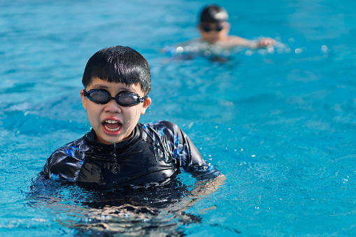 Asian children are taking swimming lessons together at the pool.