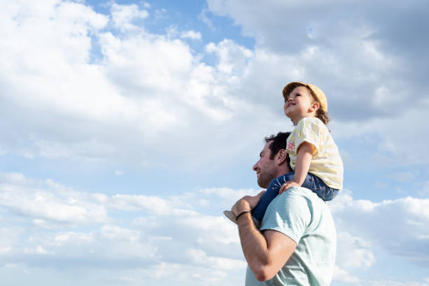 smile little girl, looking up and sitting on her father's shoulders. - father fathers day baby child imagens e fotografias de stock