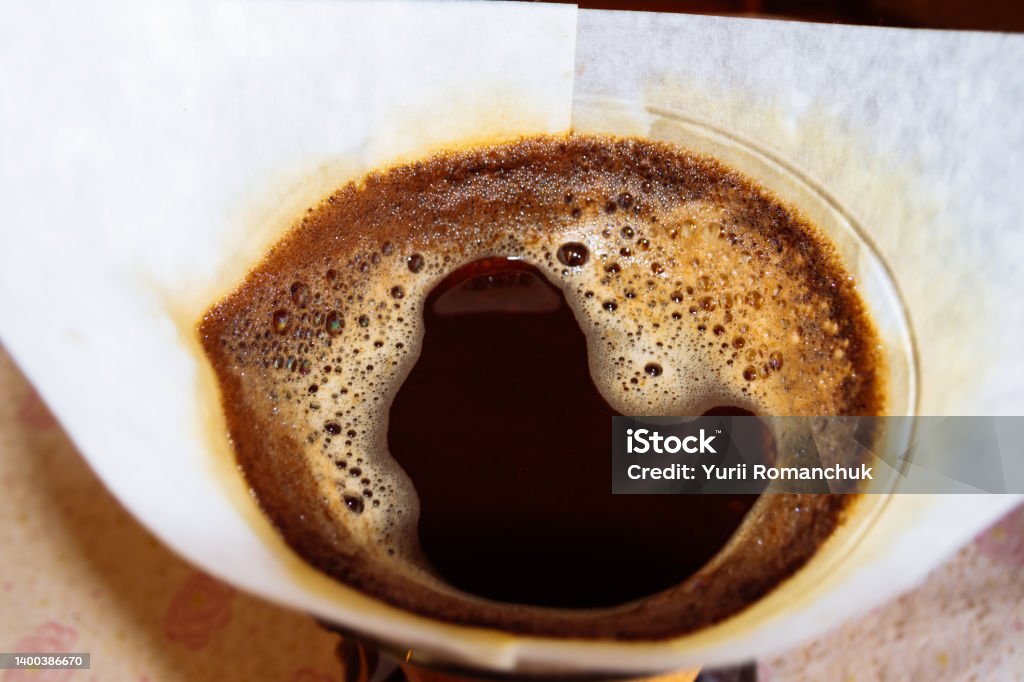 The coffee is brewed in a Chemex filter coffee maker. Coffee is filled with hot water in a white paper filter. Arabica Coffee - Drink Stock Photo