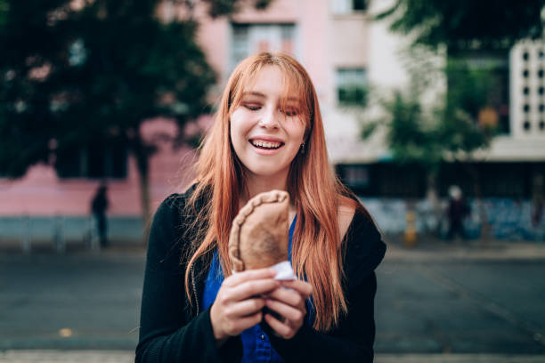 Young woman eating empanada on the streets Young woman eating empanada on the streets chilean ethnicity stock pictures, royalty-free photos & images