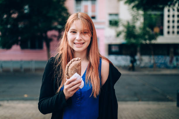 istock Young woman eating empanada on the streets 1400390432