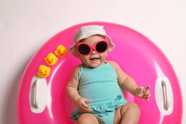 istock Cute little baby in sunglasses with inflatable ring on white background, top view 1400390886