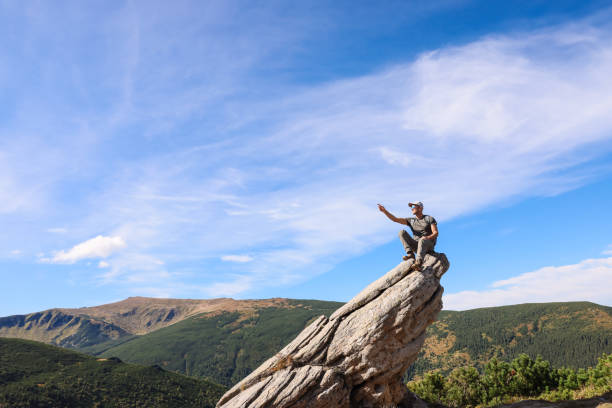 Man enjoying picturesque view on cliff in mountains. Space for text