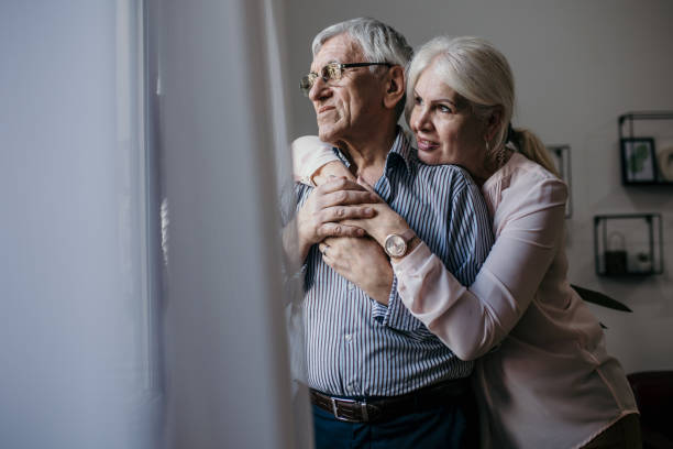 istock Senior couple embracing in front of window 1400391567