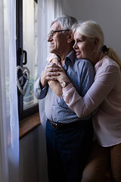 istock Senior couple embracing in front of window 1400391663