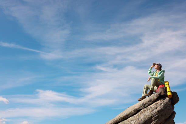 Young woman with backpack on rocky peak in mountains. Space for text