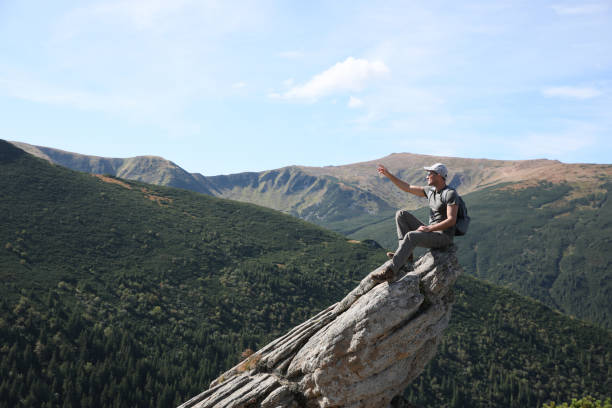 istock Tourist with backpack enjoying mountain landscape on rocky peak 1400392654