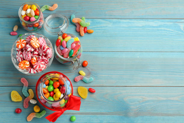 istock Jars with different delicious candies on light blue wooden table, flat lay. Space for text 1400392927
