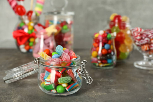 istock Jars with different delicious candies on grey table. Space for text 1400393128