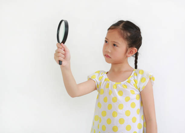 istock Surprised Asian Kid looking through a magnifying glass to beside on white background 1400394327