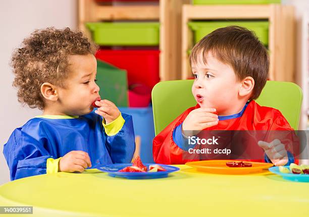 Two Toddlers Eating Fruit In A Nursery Stock Photo - Download Image Now - Eating, Toddler, Child