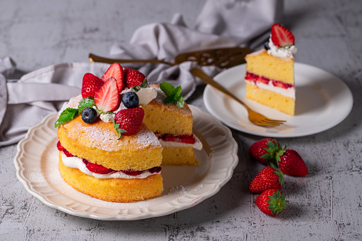 Strawberry cake on a table with summer flowers an a cup outdoors in a garden