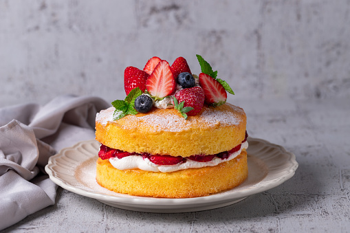 Victoria sandwich cake, decorated with strawberries, blueberries and mint closeup