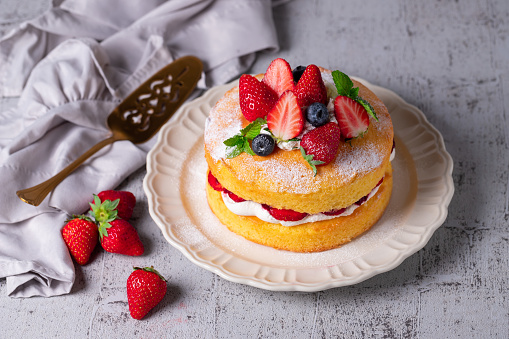 Victoria sandwich cake, decorated with strawberries, blueberries and mint closeup