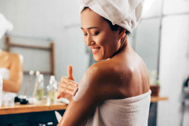 woman putting on cream after a shower - maquiagem ceremonial imagens e fotografias de stock