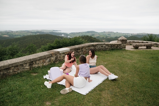 Three young women on a blanket enjoying a picnic outdoors