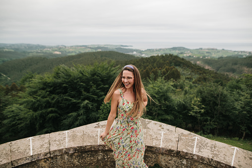 Cheerful young woman wearing a summer dress by a panoramic viewpoint