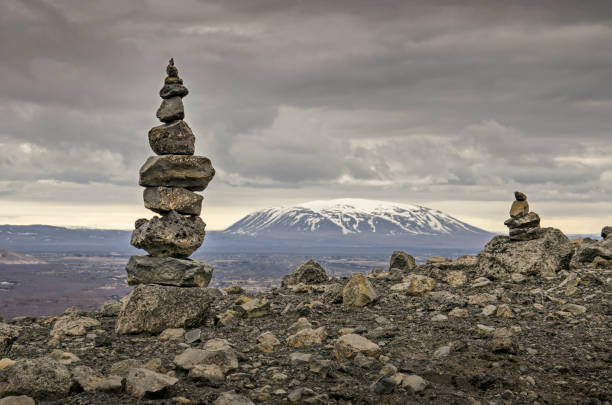 Cairns in a desolate landscape Crater rim with a tall and a lower cairn in a desolate landscape near lake Myvatn in Iceland, with a snow-capped mountain in the distance cairn stock pictures, royalty-free photos & images