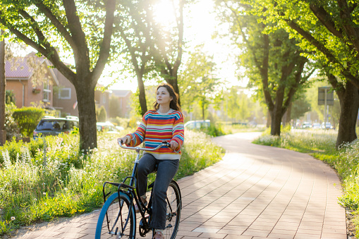 Young Caucasian woman riding bicycle on bicycle lane among the trees
