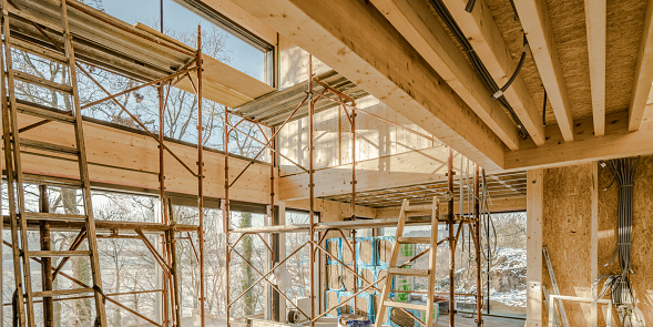 Big windows and sliding doors in large contemporary room wide view. Scaffold and ladders at building construction site low angle