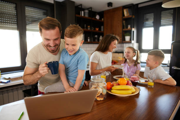 istock Father using laptop with son while rest of the family having breakfast in the kitchen 1400405202