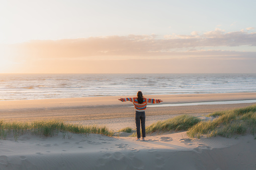 Young Caucasian woman  standing on the beach in Netherlands at sunset