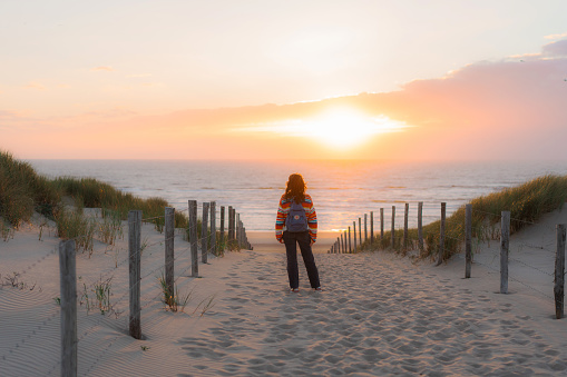Young Caucasian woman  walking on the beach in Netherlands at sunset