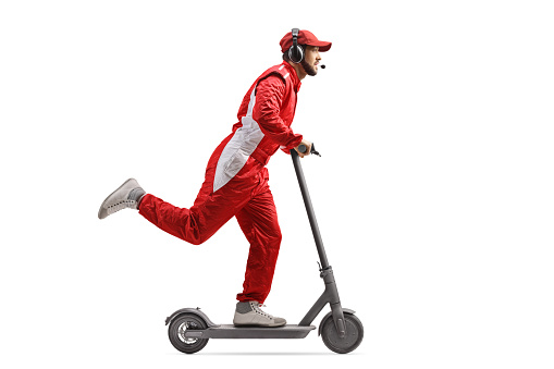 Foto de perfil de cuerpo entero de un corredor con un traje rojo montando un scooter eléctrico photo