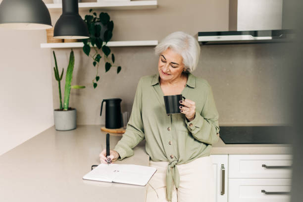 istock Carefree senior woman writing notes in her diary at home 1400407638