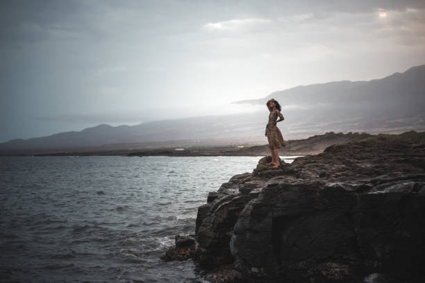 Woman standing in a cliff seashore with the ocean below