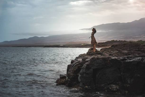 Woman standing in a cliff seashore with the ocean below