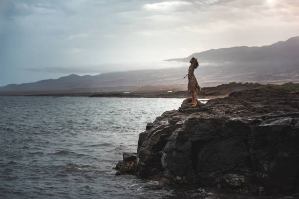 Woman standing in a cliff seashore stock photo