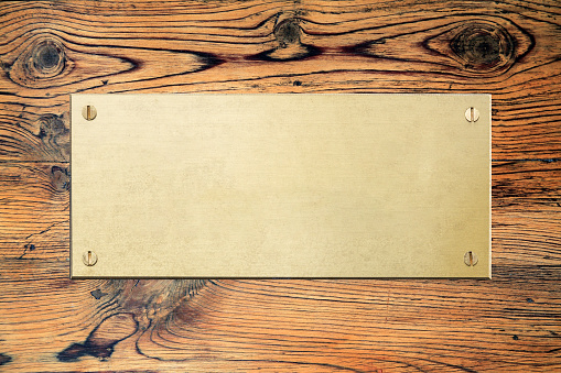 Placa de latón con textura de metal de pincel y tornillos sobre un fondo de tablero de madera photo