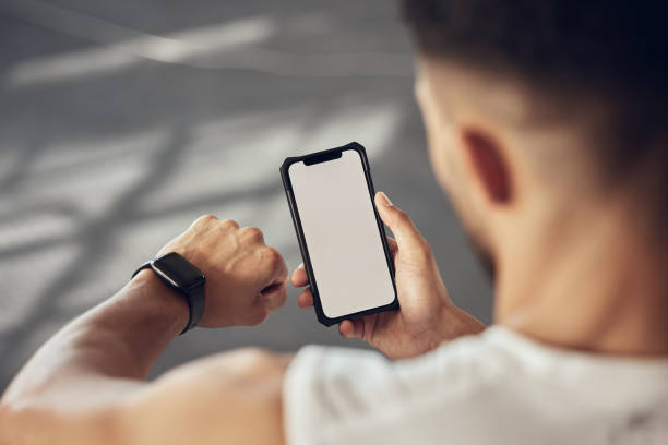 istock Athlete using their smartphone to track their progress. Fit man using a watch to track workout progress. Athlete using an online app to connect with their watch and cellphone in the gym 1400409127