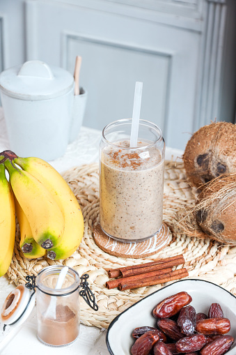 White Smoothie healthy drink with Bananas, hemp seeds, coconut oil, almond butter, cinnamon and water in rustic kitchen