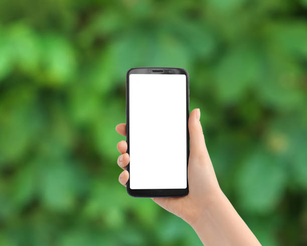 istock Hand with the phone upright against blurred greens. Smartphone with a white screen, copy space. 1400409875