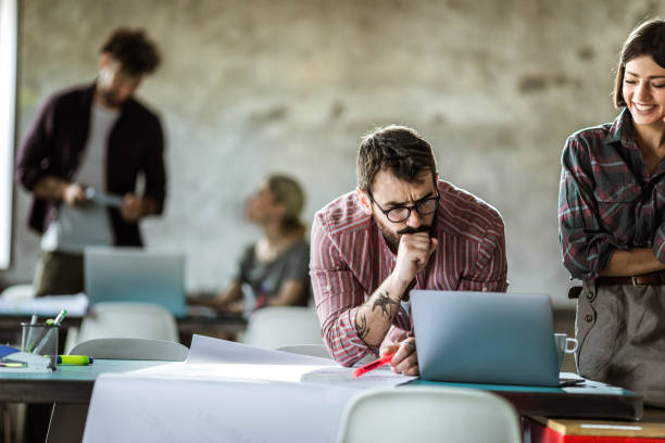 istock Design professionals cooperating while working on laptop at casual office. 1400411188