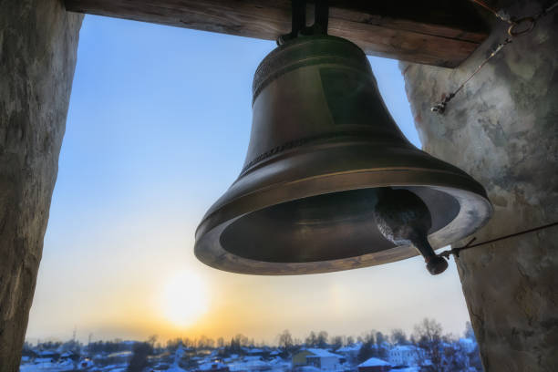pesante campana fusa nel campanile della chiesa contro il cielo giallo-blu del tramonto nell'apertura della finestra. primo piano. - campana foto e immagini stock
