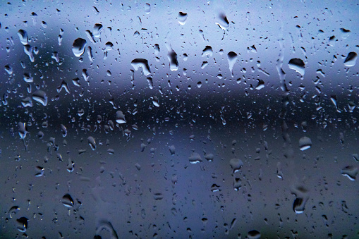 Raindrops on asphalt. Rain. Rainy weather. Car on the road. Evening twilight