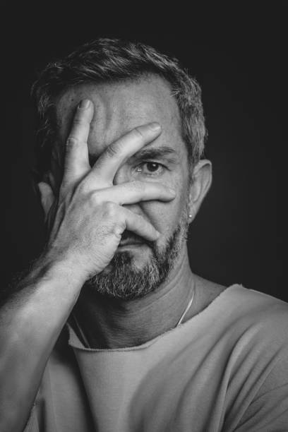 istock Mature grey haired man hide his face covered with hand looking sad or frightened. Handsome middle aged man in black and white photo. Black and white portrait of attractive, beautiful, serious man 1400412985