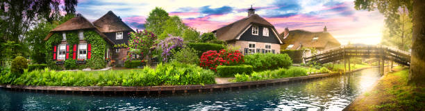 Landscape of Giethoorn village with water canals and rustic houses in netherland wide banner or panorama. stock photo