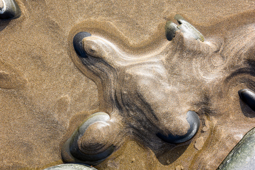 Natural abstract pattern formed by sand over pebbles at low tide